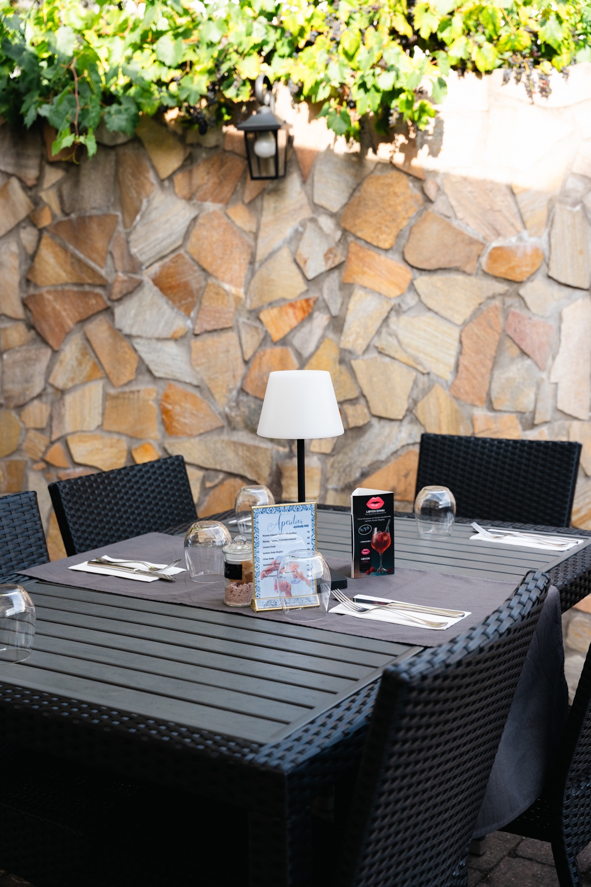 Gedeckter Tisch auf der Terrasse unter Weinreben