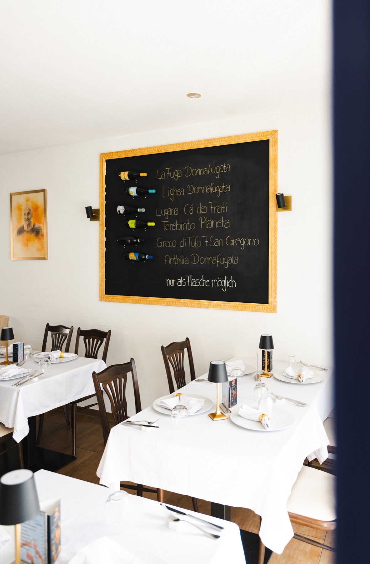 Gastraum mit Weintafel und eingedeckten Tischen
